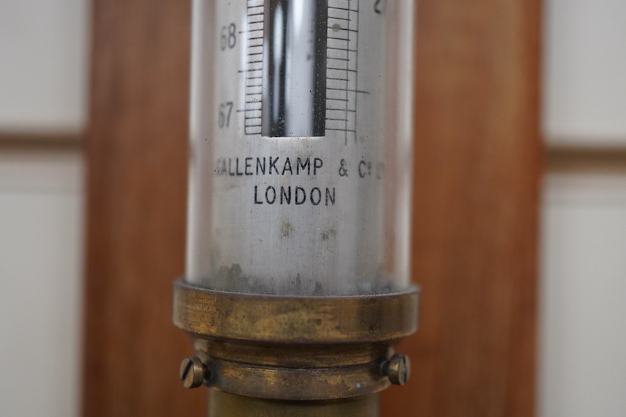 A 20th century lacquered brass marine stick barometer and thermometer by A. Gallenkamp & Co. Ltd., London, with a silvered scale, mounted on a faded oak plaque, 107cm high overall